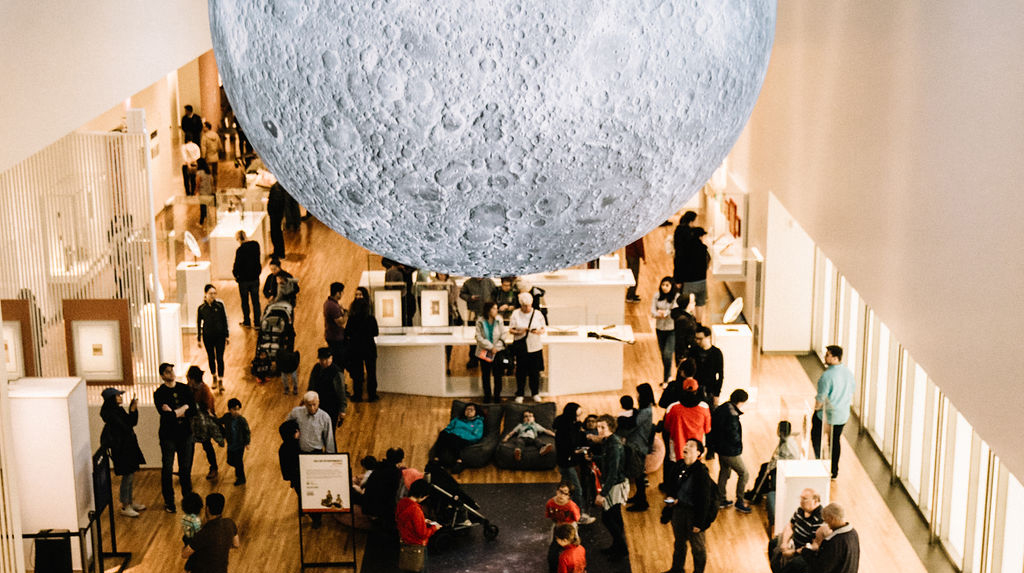 A crowd of people gather in the Museum’s permanent collection gallery under the moon.
